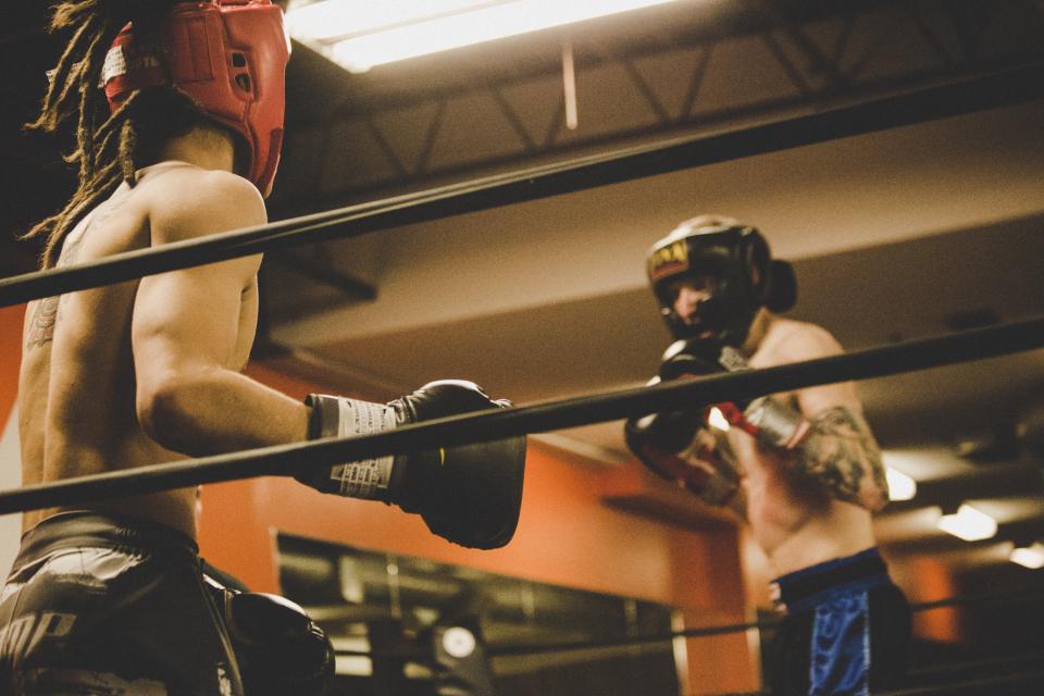 Two boxers sparring in headgear inside the ring